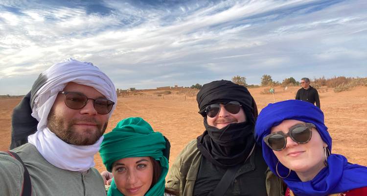 Group of people posing in traditional clothing in a desert setting.