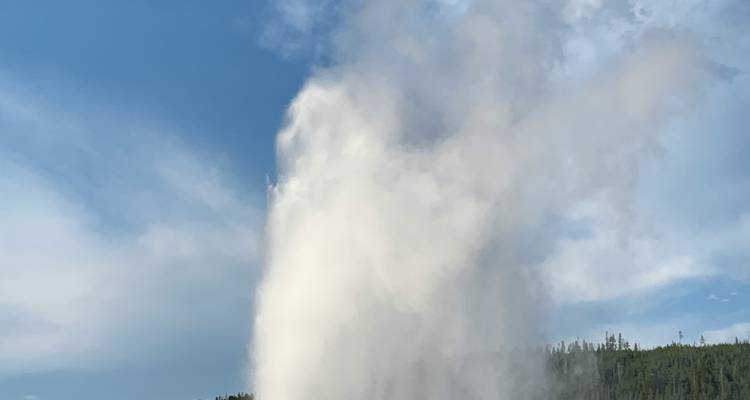 Géiser erupcionando hacia el cielo con nubes de vapor.