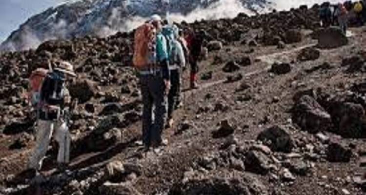 Wanderer, die ein felsiges Gelände erklimmen mit Blick auf entfernte Berge.