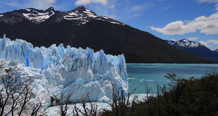 A stunning glacier with snow-capped mountains in the background.
