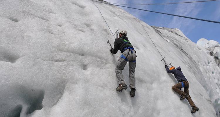 Two climbers scaling an ice wall using ropes.