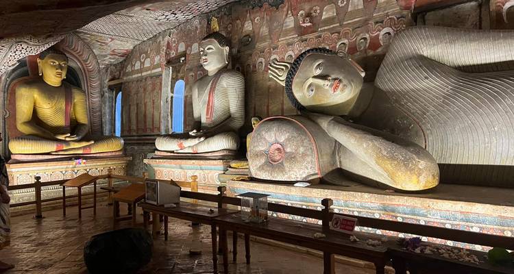 Un Bouddha couché et des figures assises illuminés à l'intérieur d'un temple rupestre historique sri-lankais.