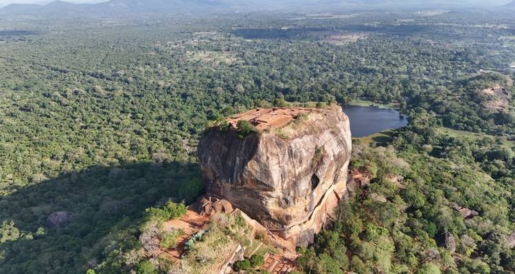 Vue aérienne du rocher du Lion de Sigiriya s'élevant au-dessus de la jungle dense du Sri Lanka avec douves et lac à proximité.
