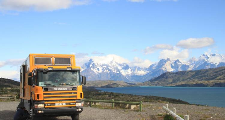 Orange truck parked with mountains in the background.