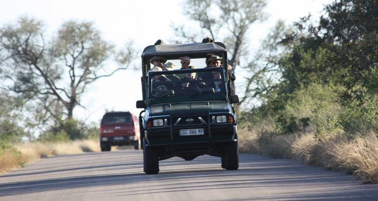 Eine Gruppe von Touristen in einem Safarifahrzeug auf einer Straße.