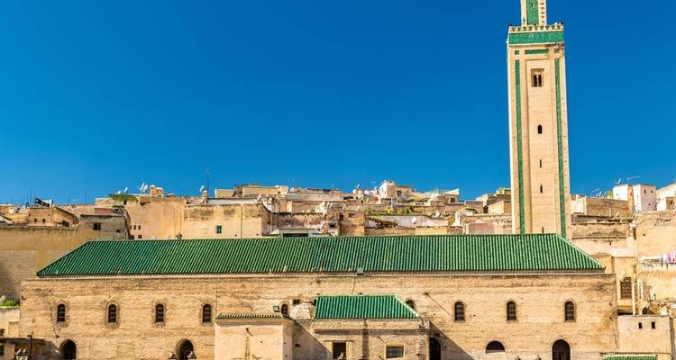 Un bâtiment historique avec un toit de tuiles vertes et un minaret élancé.