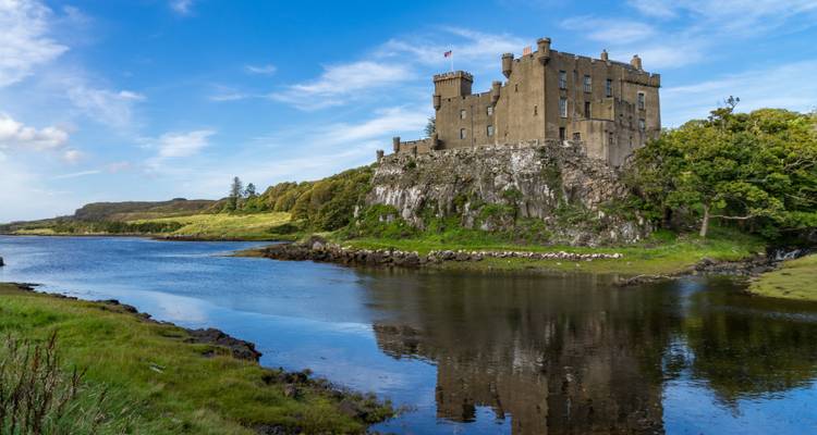 Le château médiéval de Dunvegan perché sur un promontoire rocheux se reflétant dans les eaux calmes du loch sur l'Isle of Skye