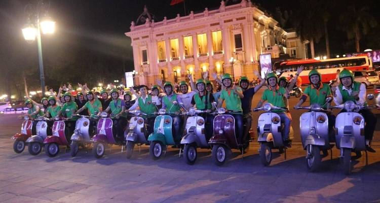 Eine große Gruppe von Menschen auf Rollern vor einem historischen Gebäude.