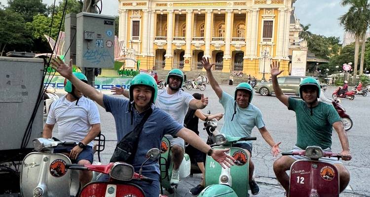 Eine Gruppe von Menschen, die auf Rollern vor einem großen Gebäude posiert.