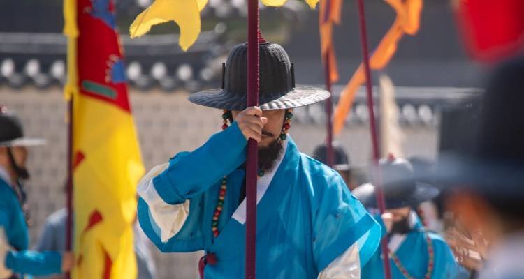 Un guardia coreano tradicional con túnica azul sostiene una bandera durante la ceremonia real del cambio de guardia.
