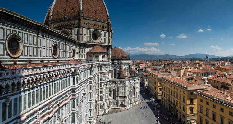 Vista cercana del complejo de la catedral de Florencia con los patrones de mármol y los tejados de la ciudad abajo