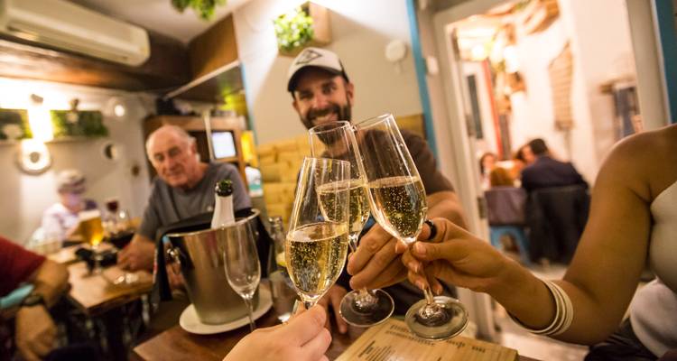 Brindis grupal con vino espumante en un ambiente acogedor de bar.