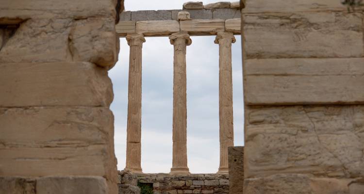 Ruins of ancient columns viewed through a stone archway.
