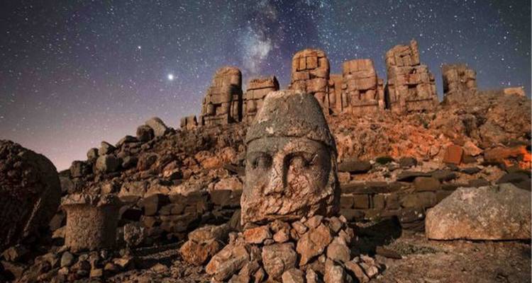 Oude stenen hoofden onder een sterrenhemel op Mount Nemrut.