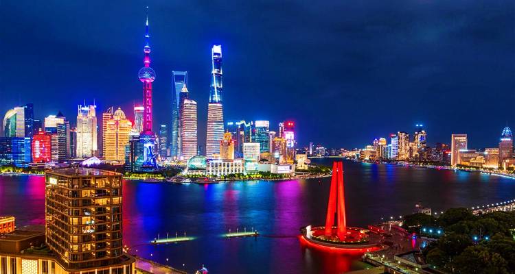 Panorama nocturne vivant de la ligne d'horizon de Pudong à Shanghai reflétée dans la rivière Huangpu avec des lumières colorées.