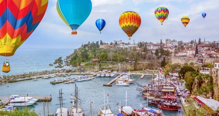 Los coloridos globos aerostáticos flotan sobre el puerto histórico de Antalya lleno de botes y yates.