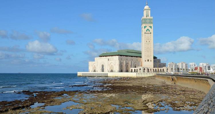 La Mosquée Hassan II se dresse sur le littoral atlantique avec l'horizon urbain et un ciel bleu en arrière-plan.