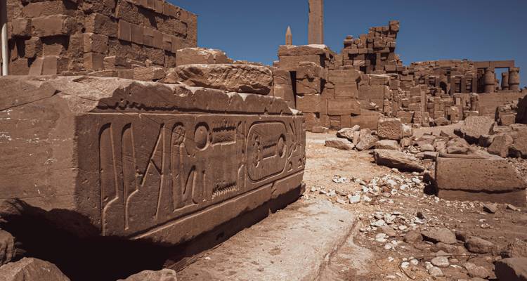 Ruinas del antiguo Egipto con jeroglíficos bajo un cielo azul despejado.