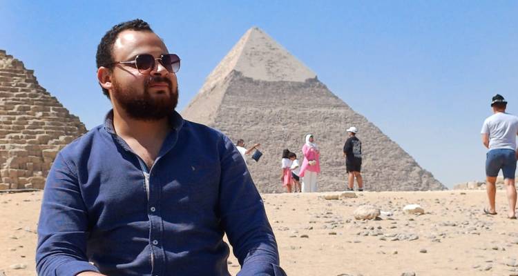 Una persona posando con las pirámides en el fondo.