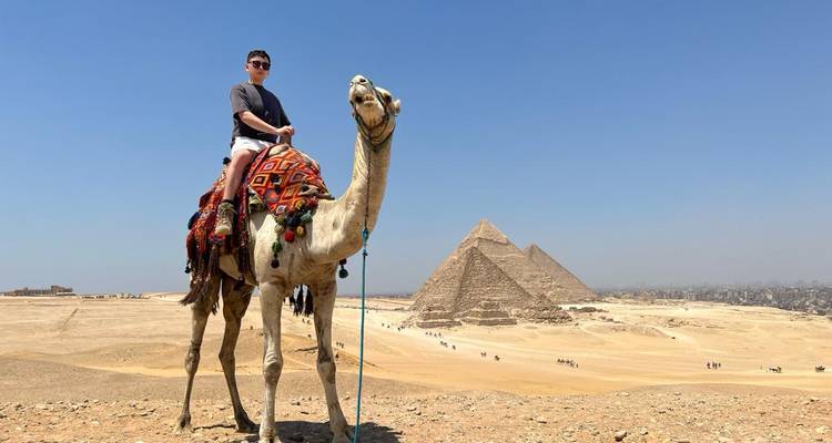 Persona en un camello frente a las pirámides en el desierto.