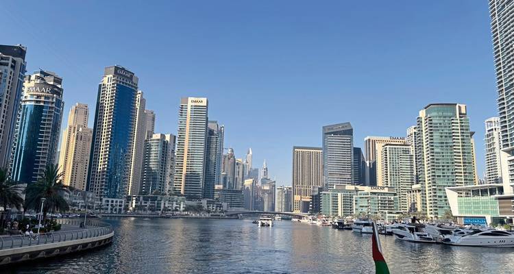 Moderne Wolkenkratzer der Dubai Marina säumen die Wasserstraße mit Yachten unter klarem Himmel