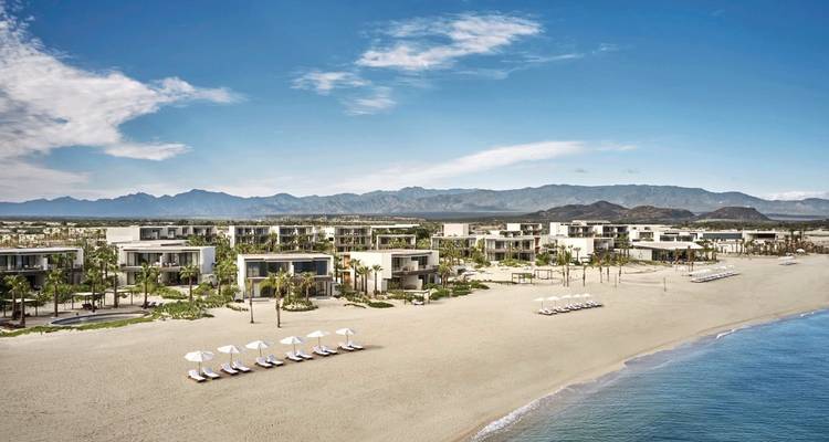 Luftaufnahme eines Strandes mit Luxusresort und klarem blauem Wasser.