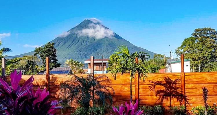 Volcan avec le sommet couvert de nuages sous un ciel clair.