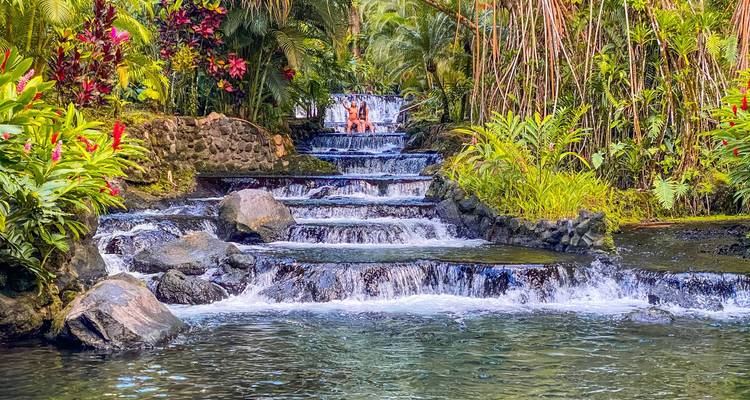 Cascade tropicale avec une végétation luxuriante et des gens profitant de l'eau.