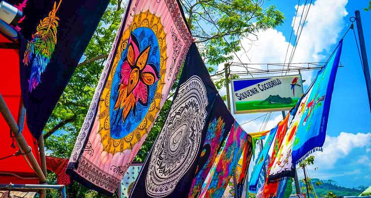 Tapices y estandartes coloridos colgando en un puesto del mercado.