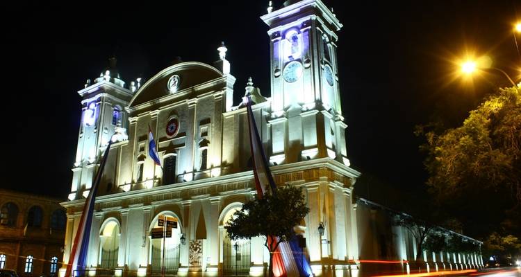 Beleuchtetes Gebäude bei Nacht mit Flaggen und Lichtern.