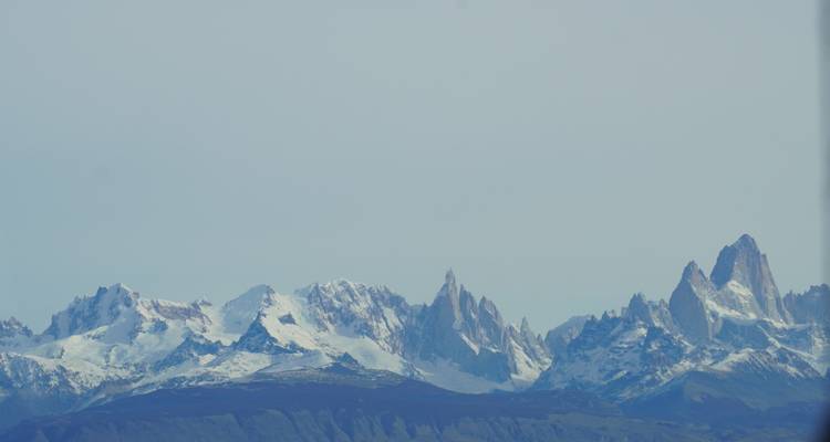 Bergketen met besneeuwde toppen onder een heldere hemel.