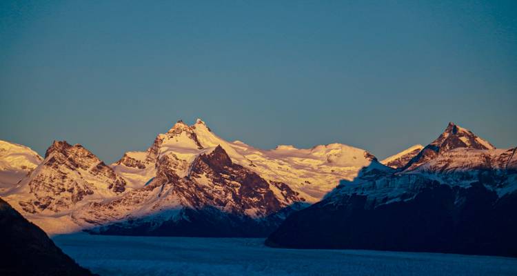 Met sneeuw bedekte bergen verlicht door zonlicht tijdens zonsondergang.