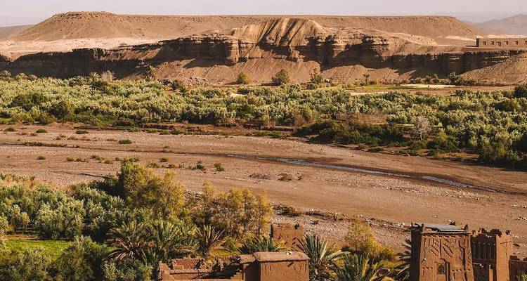 Groene oase met een rivierbed omringd door dor landschap.
