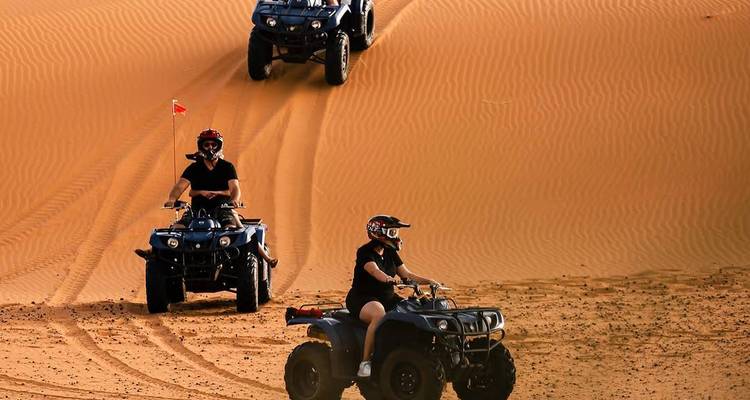 Mensen die op ATV's rijden op woestijnzandduinen.
