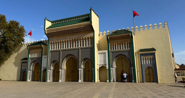 Portail historique avec une architecture ornementée verte et beige et des drapeaux.
