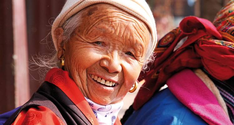 Femme âgée souriante portant des vêtements traditionnels.