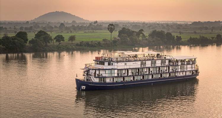 River cruise ship sailing during sunset on a calm river.