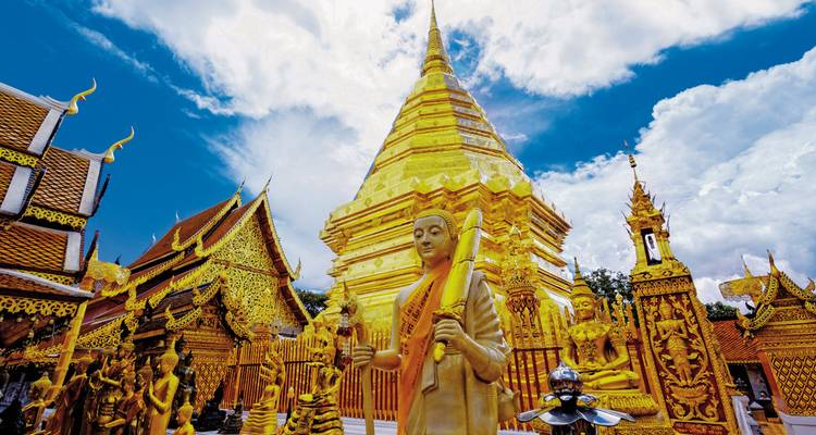 Golden Buddhist temple with intricate details and blue sky.