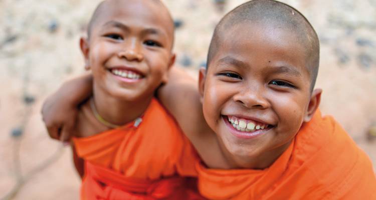 Two young monks smiling with arms around each other.