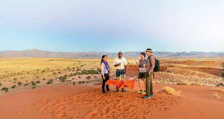 Group of people having a meal on sand dunes.