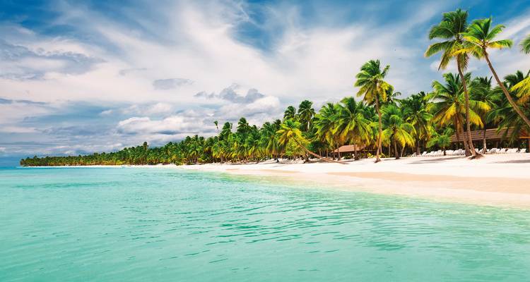 Palmengesäumter Strand mit weißem Sandstrand und türkisfarbenem Meer.