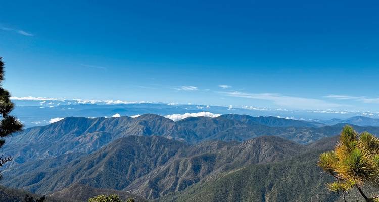 Vue panoramique de chaînes de montagnes sous un ciel bleu éclatant.