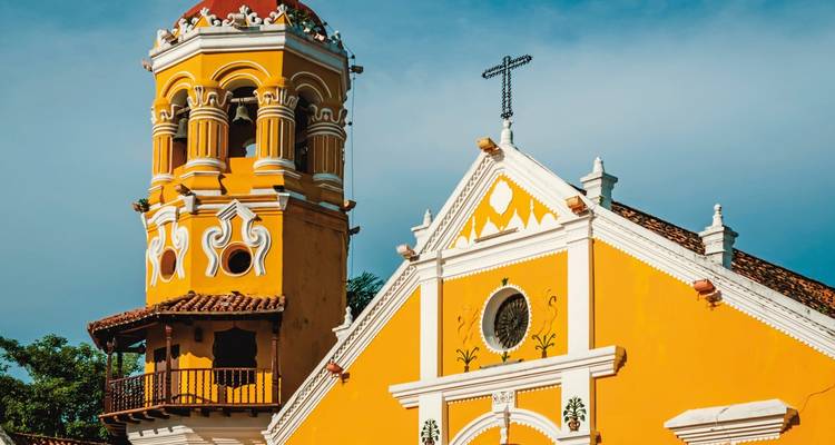 A yellow colonial church tower with intricate designs.