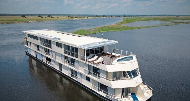 Houseboat on a river surrounded by open landscapes.