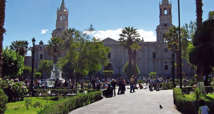 Belebter Stadtplatz mit einer Kathedrale und gehenden Menschen.