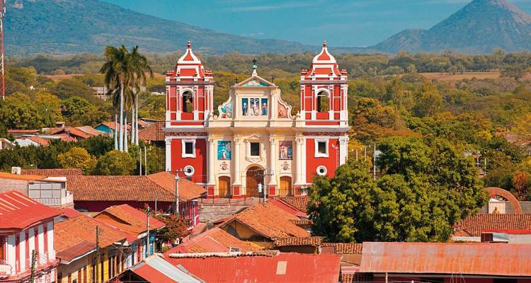 Église colorée à Grenade avec des montagnes en arrière-plan.