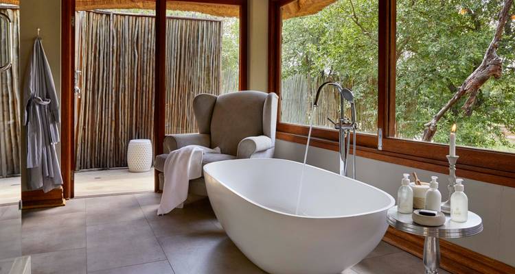 Luxurious bathroom with a freestanding bathtub and large windows overlooking nature.