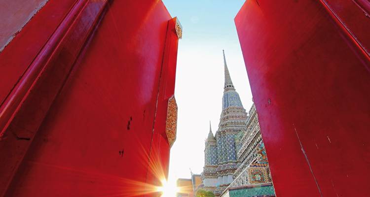 Red gates opening to a temple with sunlight shining.