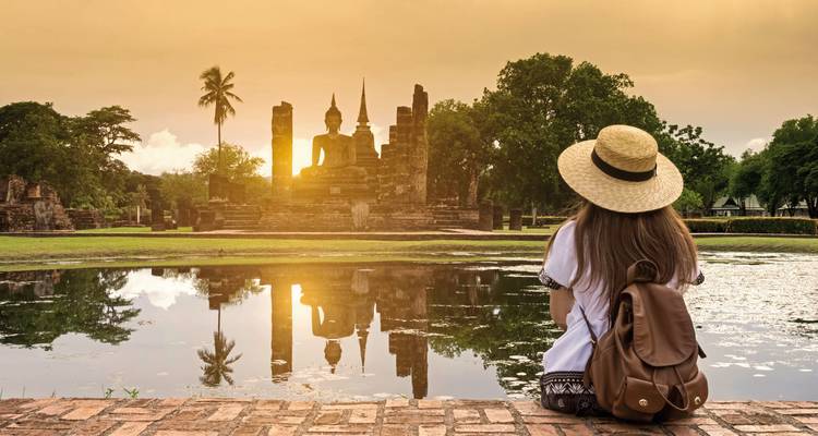A woman in front of a temple reflection during sunset.