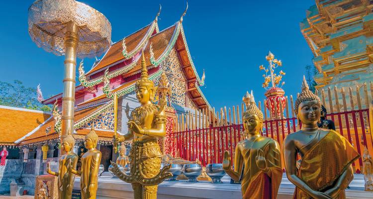 Golden Buddha statues and temple architecture under a clear sky.